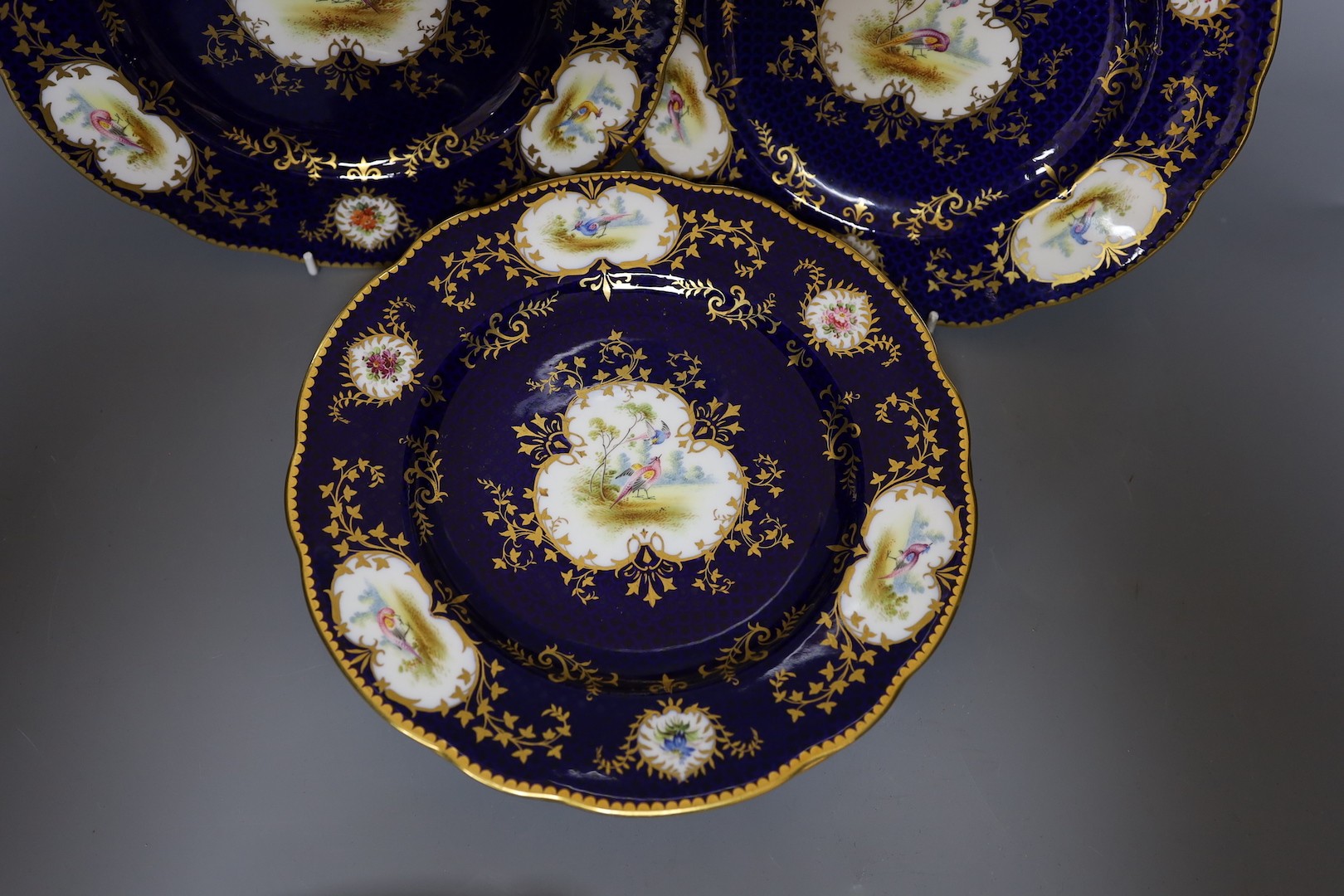 A Late 19th/early 20th century Coalport set of six plates and a square dish, which is signed F Howard, one plate signed P Simpson and four plates initialled PHS for Percy Simpson, Coalport crown England mark and T Goode